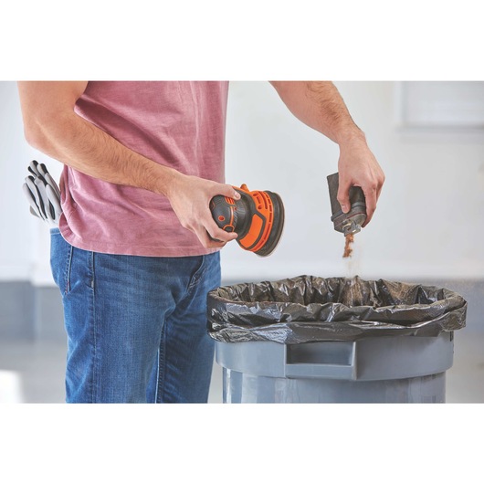 20 volt MAX Cordless Random Orbital Sander being cleaned over a dustbin by a workman.