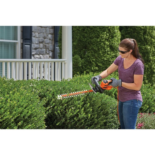 22 inch SAW BLADE Electric Hedge Trimmer being used by a person on a hedge.